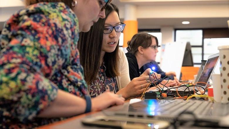 Two women work with Hummingbird Duo robotics kit